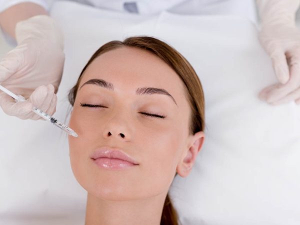 partial view of young woman getting beauty injection made by cosmetologist in salon